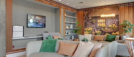 A modern living room with a grey sofa, a television, and a wooden wall with a neon sign.