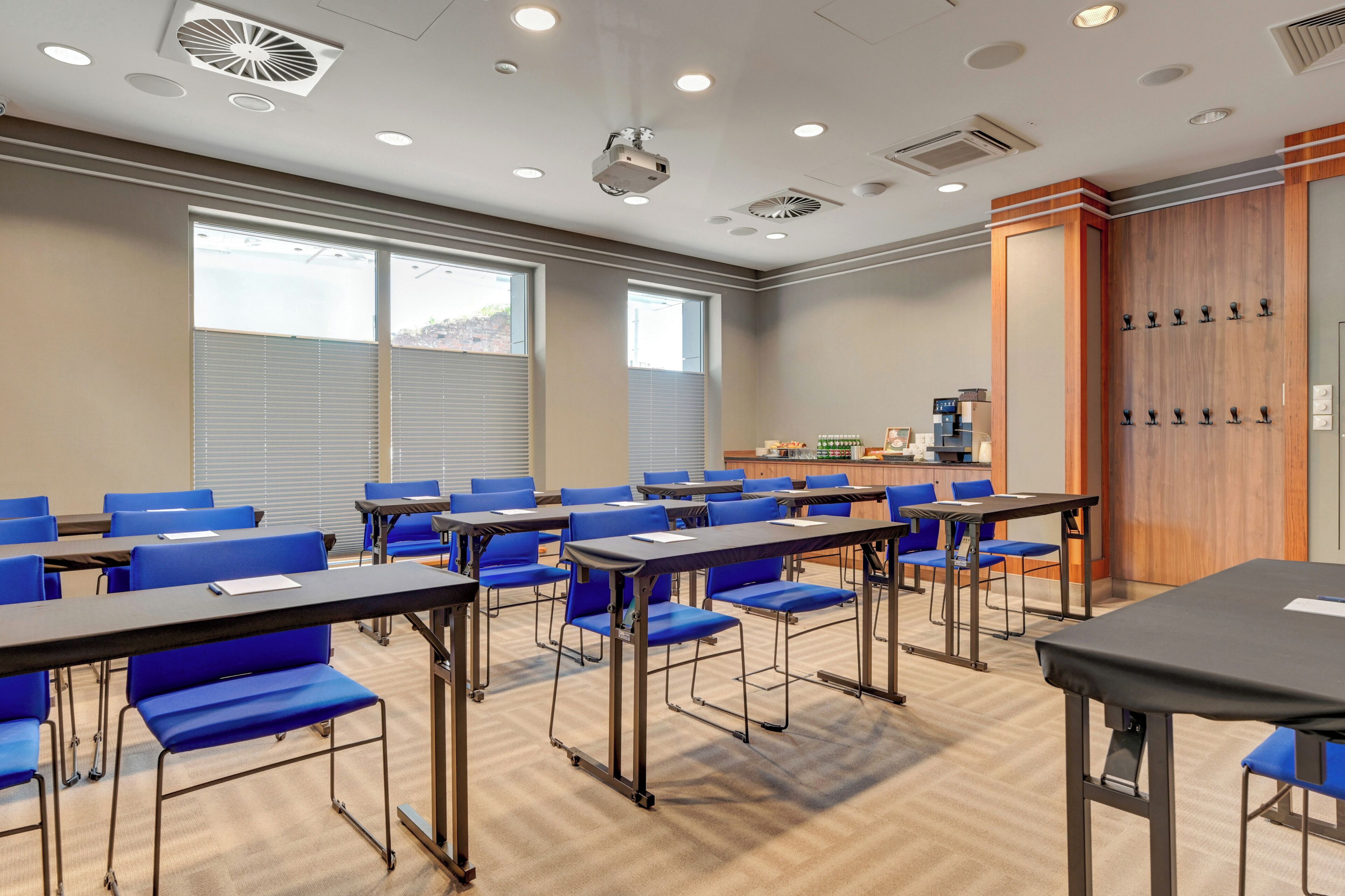 A conference room with tables, chairs, a podium, and a window with blinds.