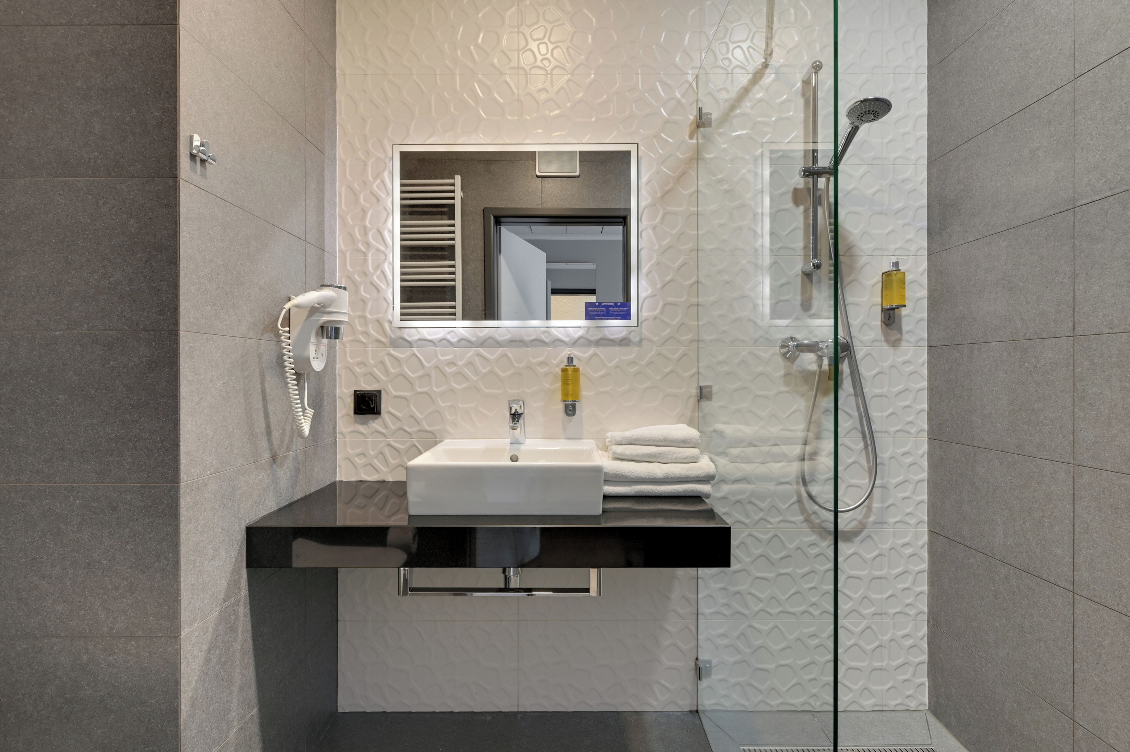 A bathroom with a white sink, mirror, and shower.