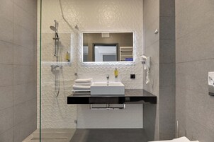 A modern bathroom with a glass-enclosed shower, a white sink, and a mirror above it.