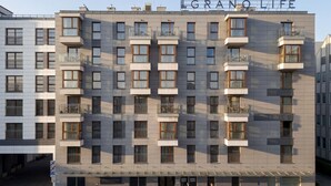 Un hotel de varios pisos con balcones, un cartel visible que dice 'GRANOLIFE' y una entrada a nivel de calle.