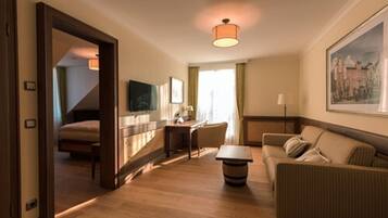 A hotel room with a bed, a desk, a sofa, and a dining table.
