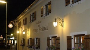 Un edificio con varias ventanas, algunas con contraventanas, y un letrero encima de las ventanas.