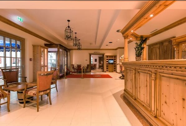 A spacious lobby with wooden furniture, a reception desk, and a chandelier.