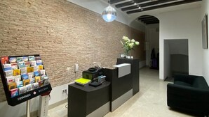 Una moderna zona de recepción con pared de ladrillo, un mostrador de recepción, un expositor de bienvenida y un área de estar con un sofá.