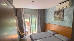Una habitación de hotel moderna con una cama grande, un armario, una mesita y vistas a través de un ventanal.