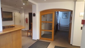 A reception area with a wooden desk, a reception sign, a fire extinguisher, and a staircase leading to an upper floor. - Hotel Alt Steinbach (Steinbach)