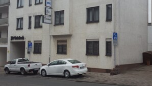 A multi-story building with a flat facade, several windows, and a parking sign. - Hotel Alt Steinbach (Steinbach)