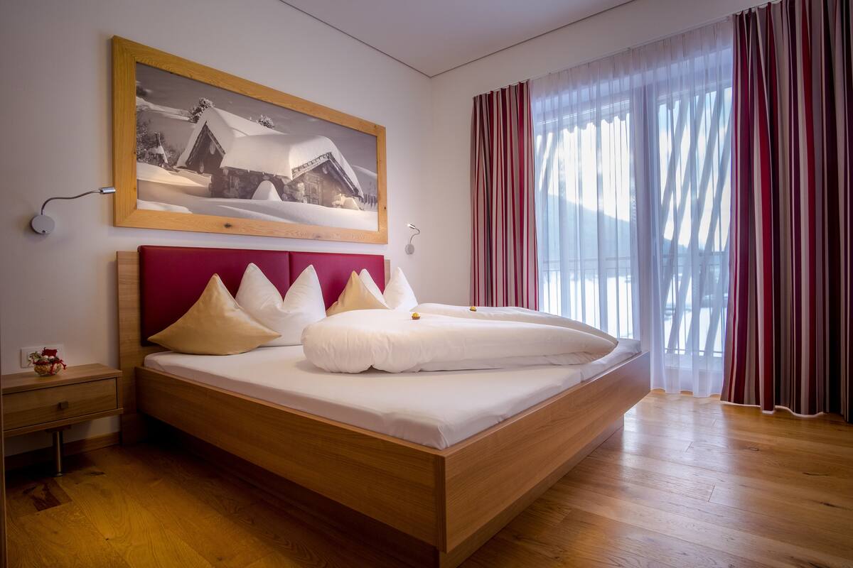 A modern bedroom with a wooden bed, a red headboard, and a framed picture on the wall.