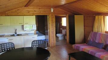 Interior de una cabaña con cocina, comedor y sofá.