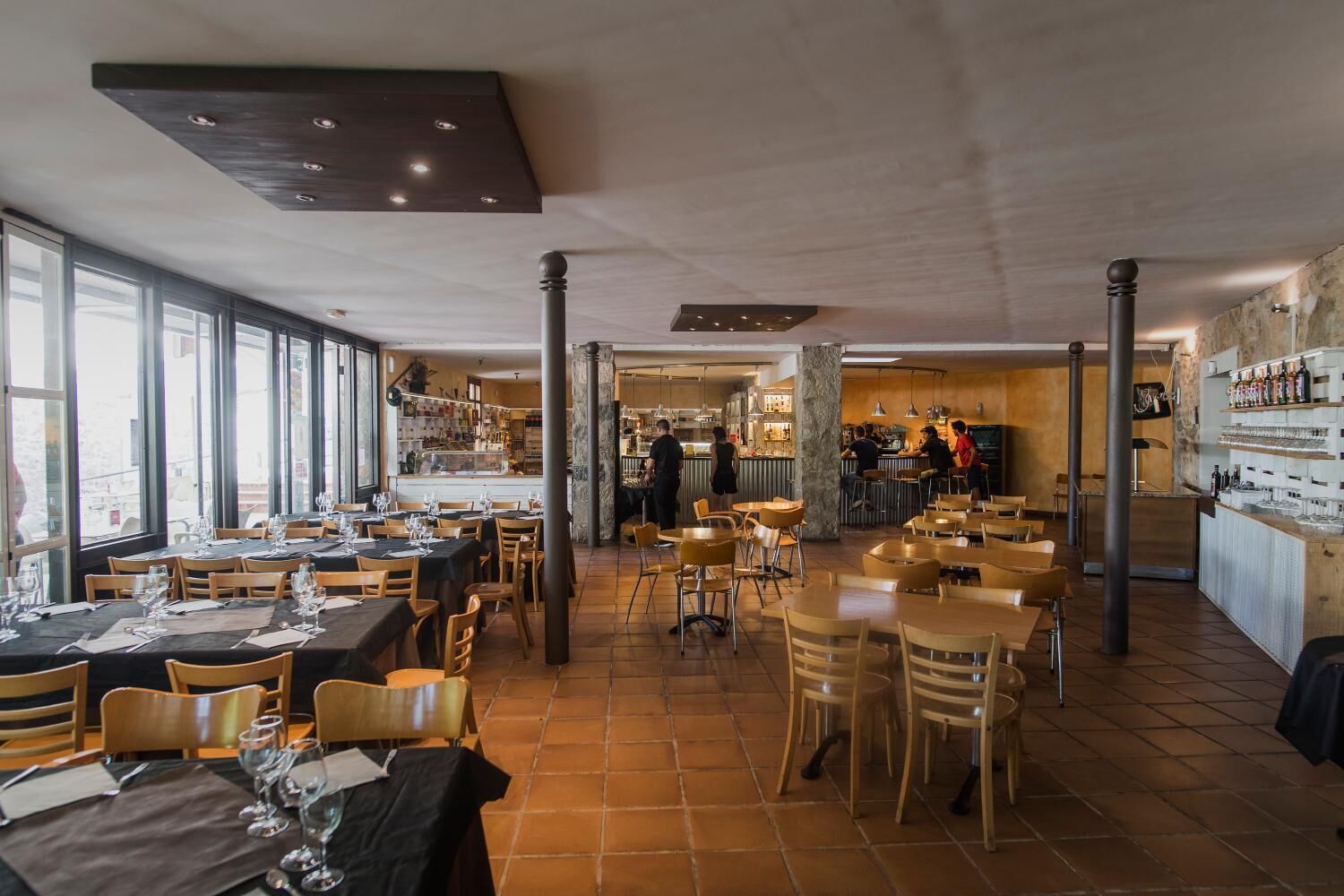 Un restaurante con varias mesas, sillas y una zona de bar.