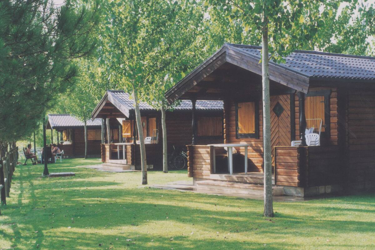 A row of log cabins with a covered porch and a bicycle parked outside.