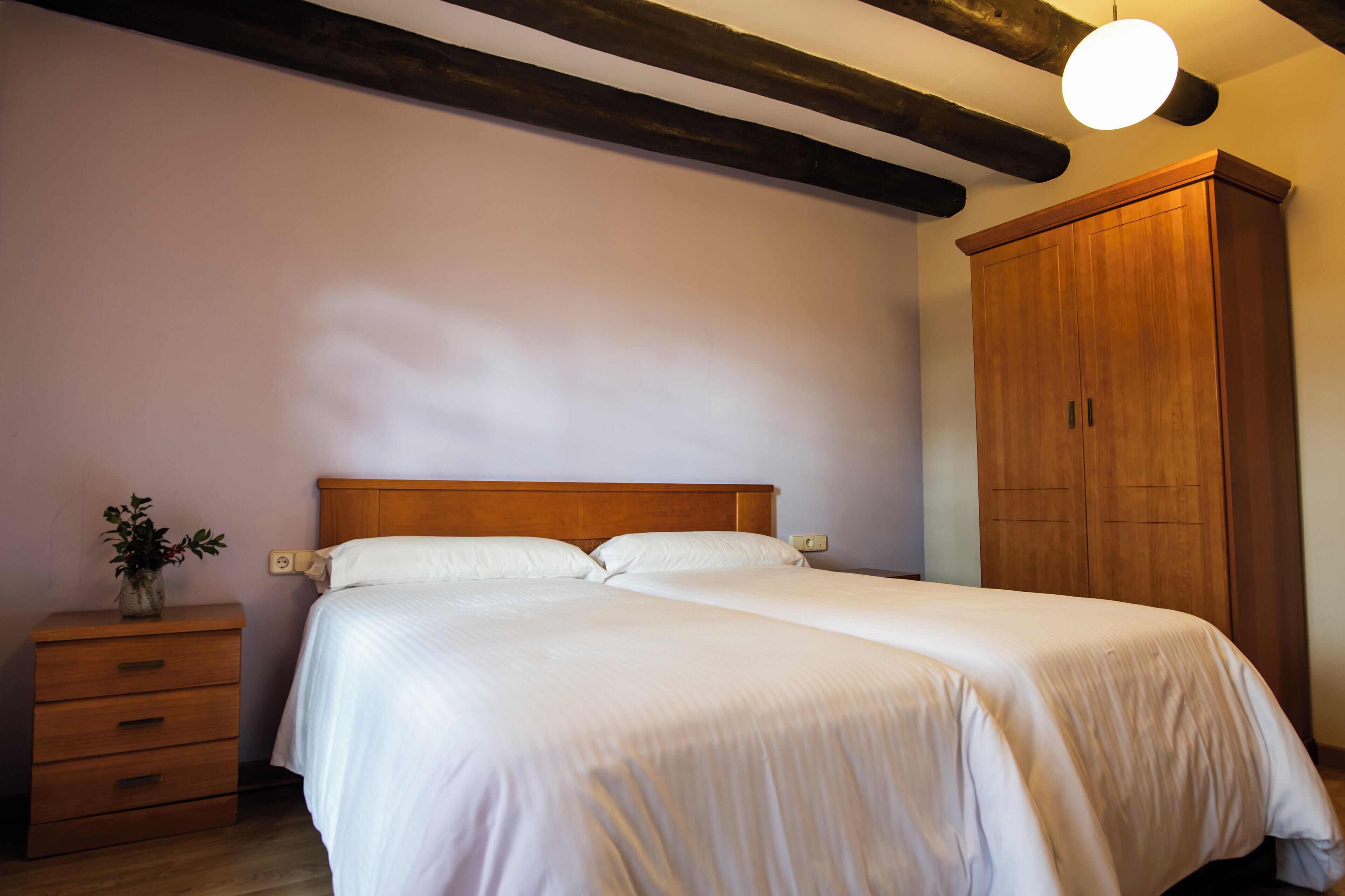A bedroom with a wooden bed, a nightstand, a dresser, and a wardrobe.