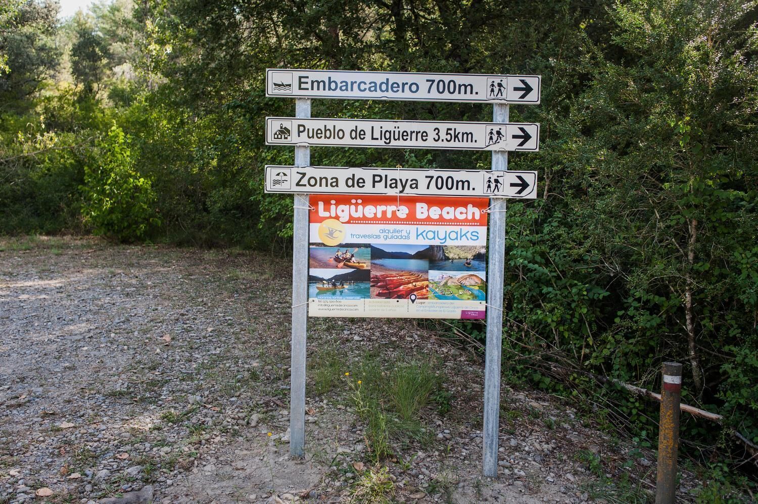 Un panneau de signalisation indiquant les directions et les distances vers différentes destinations, notamment : « Embarcadero, 700 m », « Pueblo de Liguere, 3,5 km » et « Zona de Playa, 700 m ».
