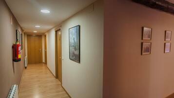 Un pasillo con piso de madera, un extintor y cuadros en las paredes.