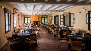 A long dining room with multiple tables and chairs, large windows, and a fireplace. - Camping & Bungalows Ligüerre de Cinca (Abizanda)