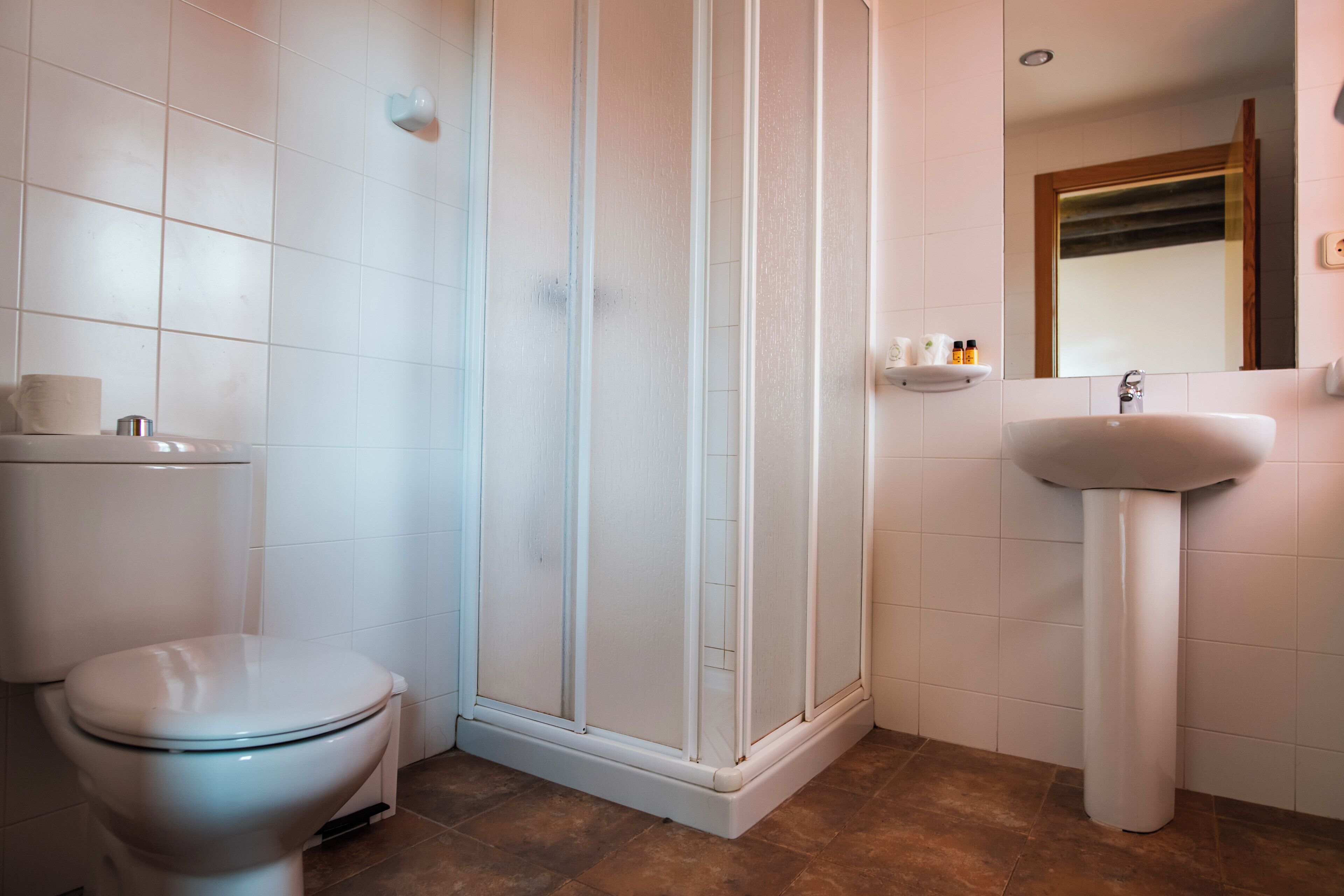 A bathroom with a toilet, a shower enclosure, and a sink.