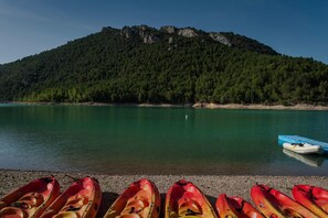 Ein ruhiger See mit am Ufer angelegten Kajaks und einem Berg im Hintergrund.