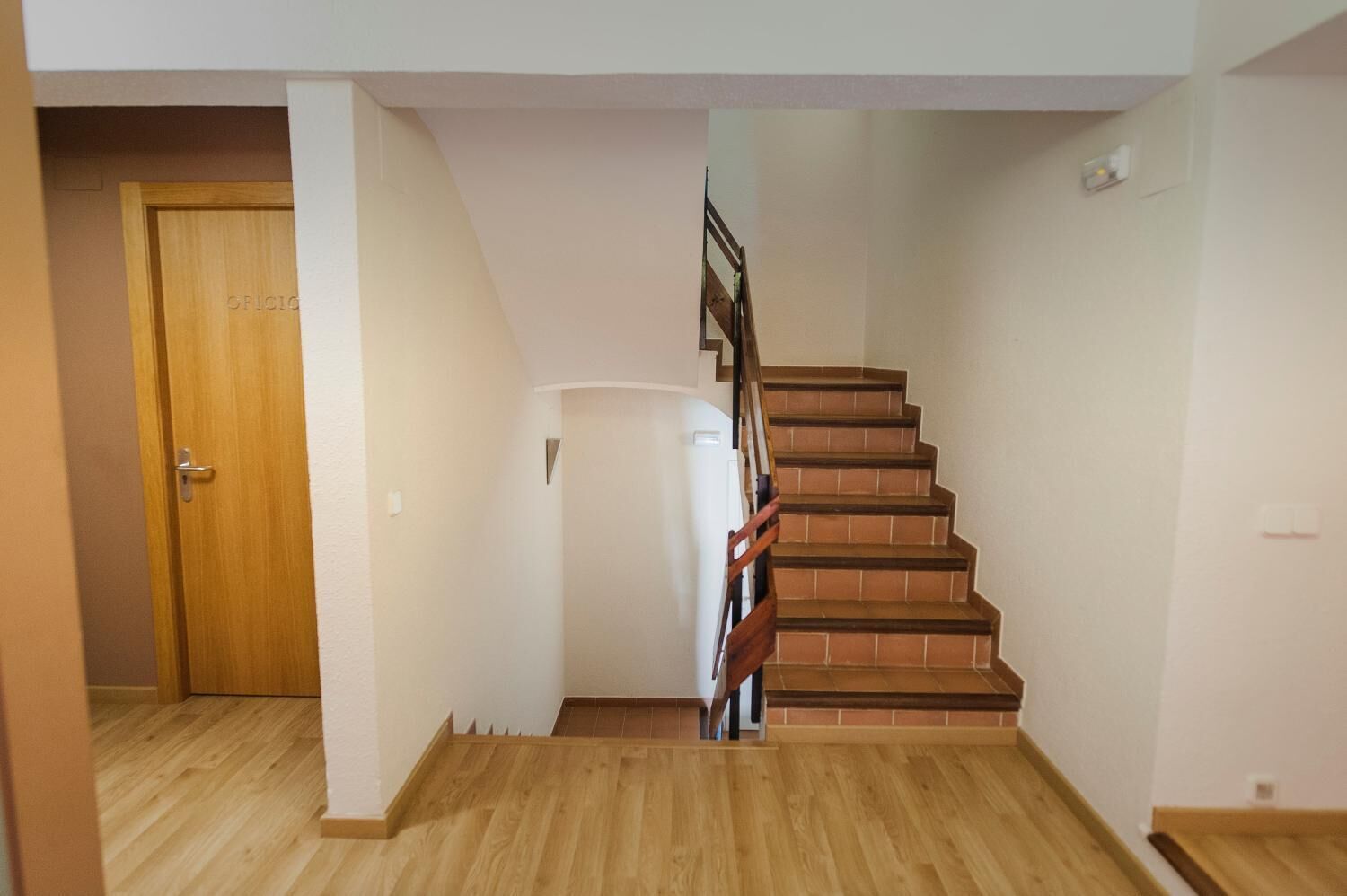 A staircase with wooden steps and a handrail, leading to a landing with a white door.