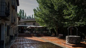 A courtyard with a stone fountain, outdoor seating area, and a building with a tiled roof. - Camping & Bungalows Ligüerre de Cinca (Abizanda)