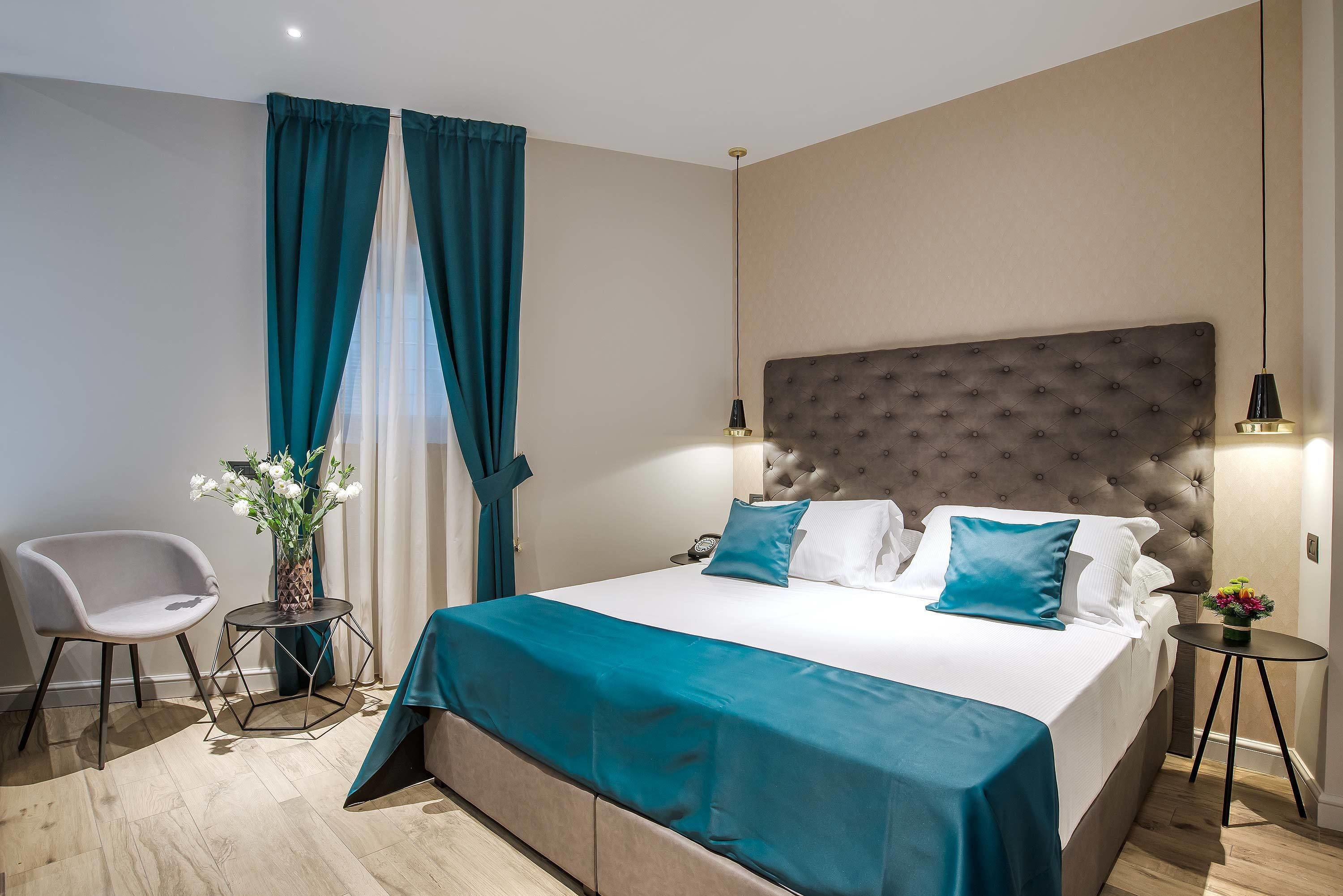 Una habitación de hotel moderna con una cama grande, una pequeña mesa redonda, una silla y un florero con flores.
