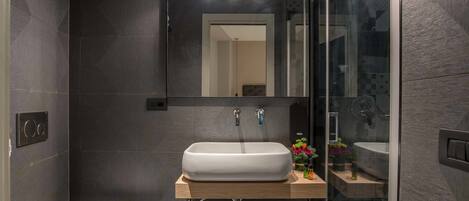 A modern bathroom with a white sink, a toilet, and a glass shower enclosure.