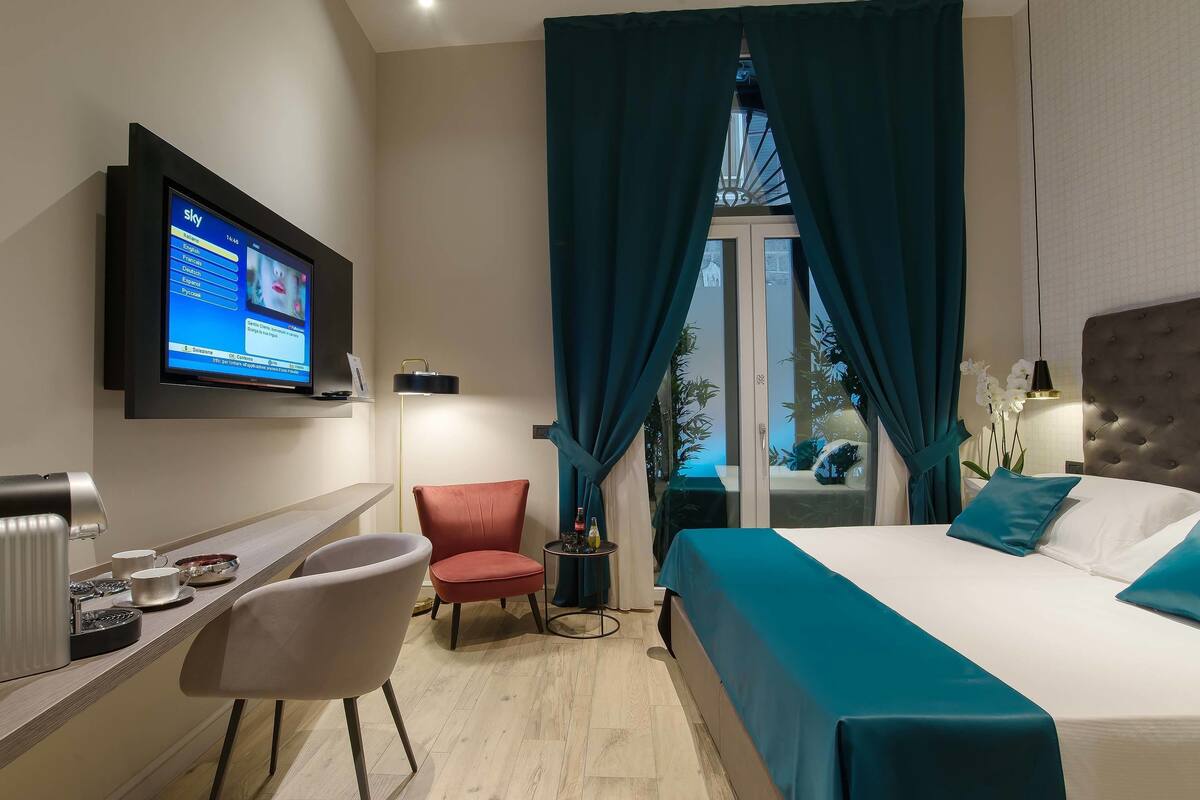 A hotel room with a bed, a desk, a chair, a television, and a view of the outdoors.