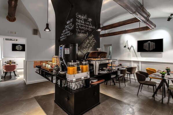 Una cuina moderna amb un racó de cafè, electrodomèstics d'acer inoxidable i una pissarra amb missatges motivacionals.