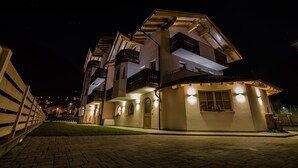 Un hotel de varios pisos con balcones, entrada empedrada de ladrillo e iluminación cálida.