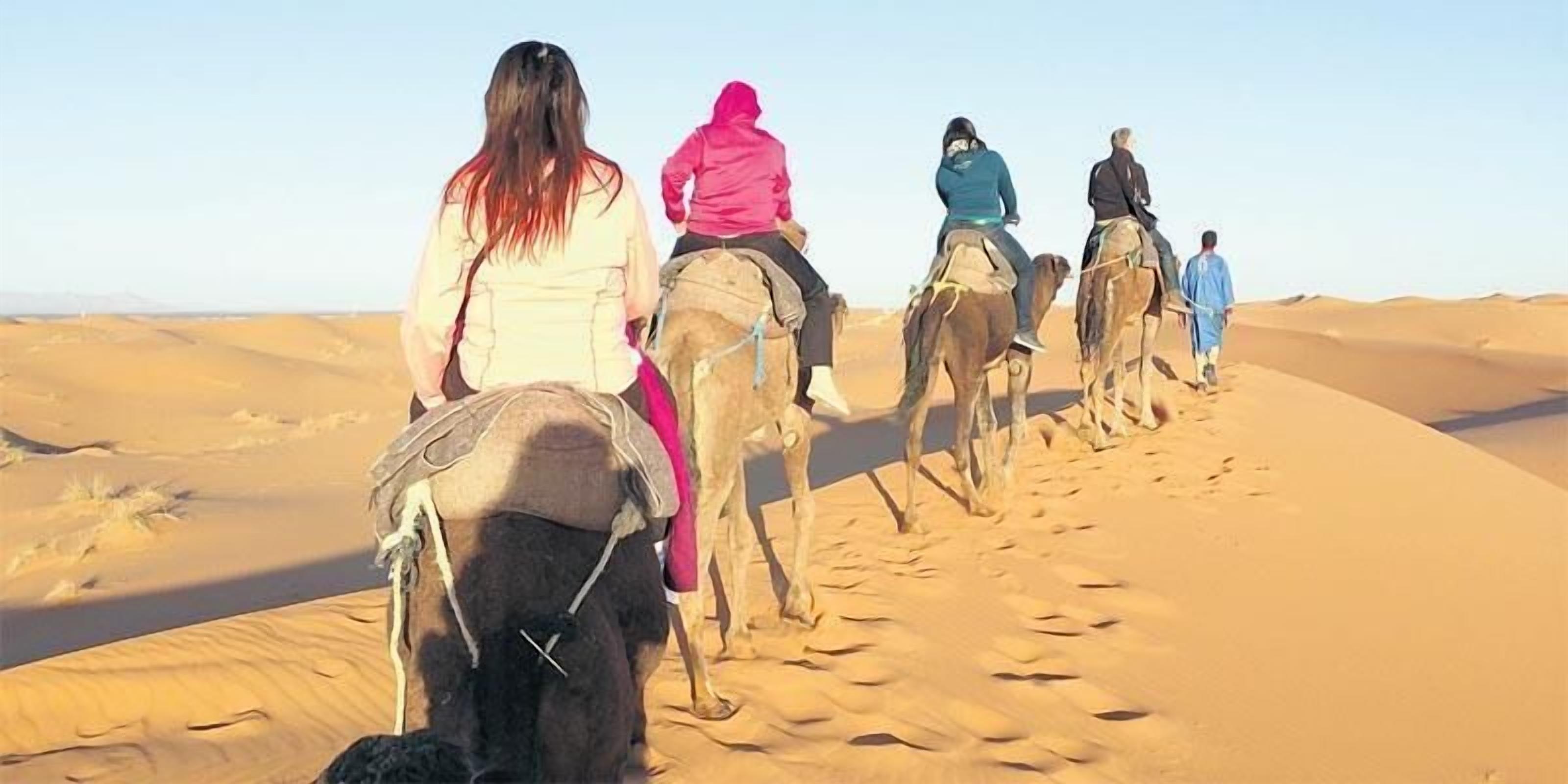A group of people riding camels in a desert.