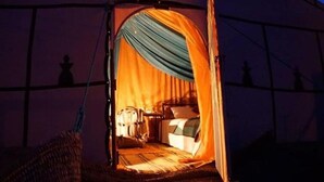 Una carpa con una cama en su interior, una mesita y una silla.