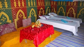 Una habitación con dos camas, una mesa con fruta y paredes con diseño.