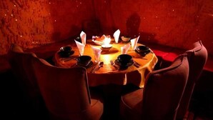 Una mesa redonda para comer con sillas, velas y platos.