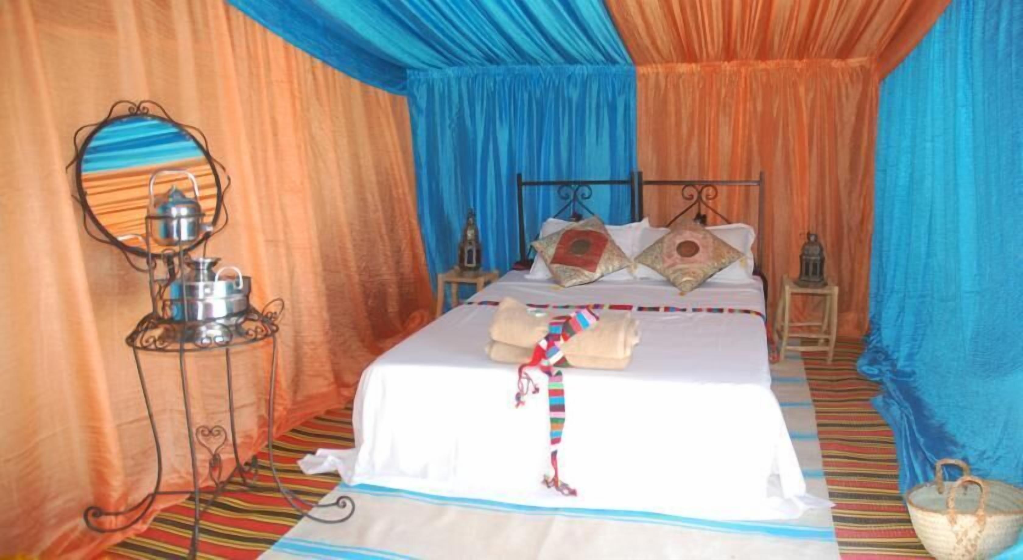 A room with a bed, a bedside table with a lamp, and a hanging lamp.