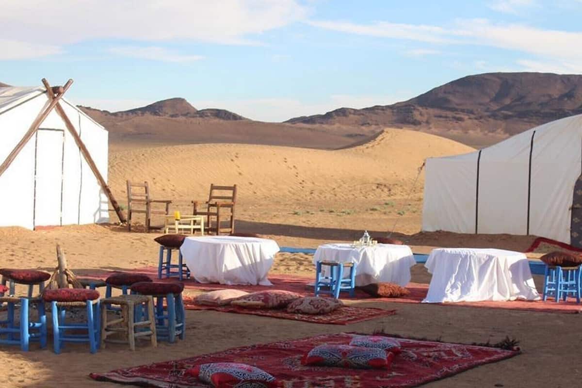 Un terrain de camping aménagé dans le désert, avec des yourtes, des tables et des chaises installées sur le sable.