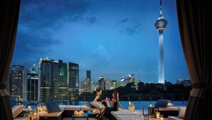 Terraza en la azotea con asientos y mesas, con vistas a un horizonte urbano y una torre.