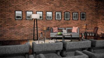 A living room with a brick wall, a sofa, armchairs, a coffee table, and framed pictures.