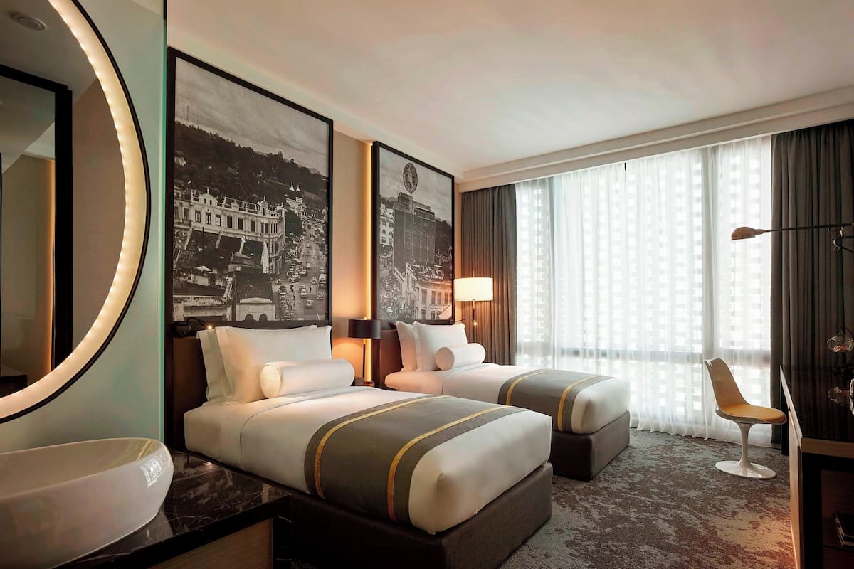 Ein Hotelzimmer mit zwei Betten, einem großen Spiegel, einem Schreibtisch und einem Stuhl.