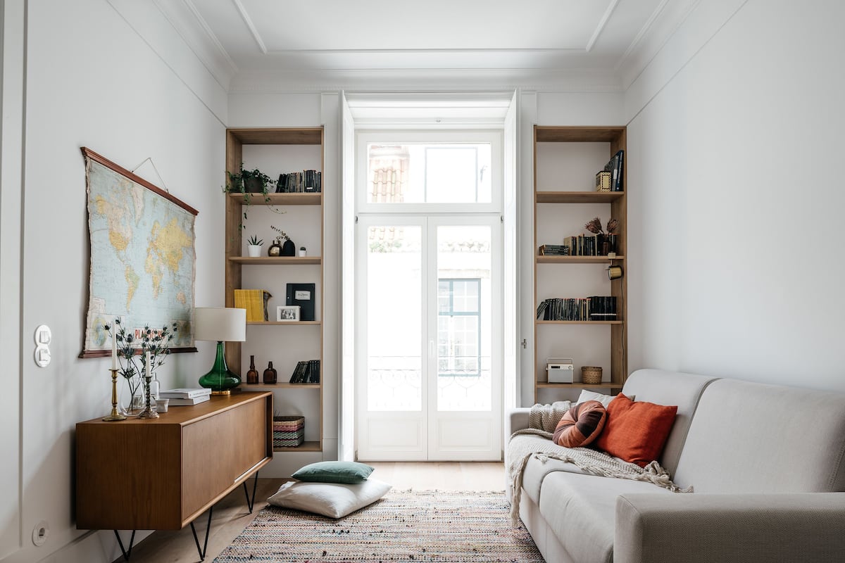 Un salon chaleureux avec un canapé, une table basse, une bibliothèque et une carte du monde accrochée au mur.