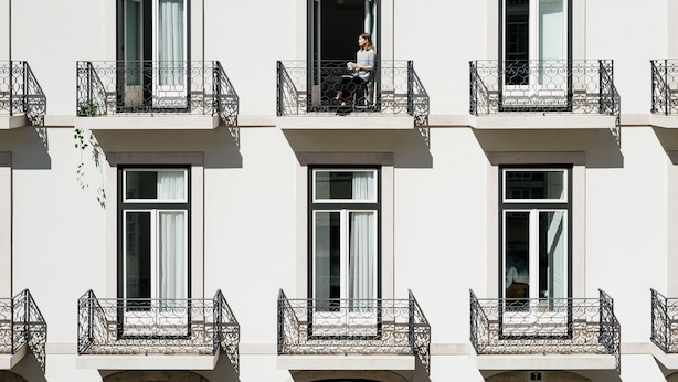 A building with multiple balconies, each with a wrought iron railing and a window.