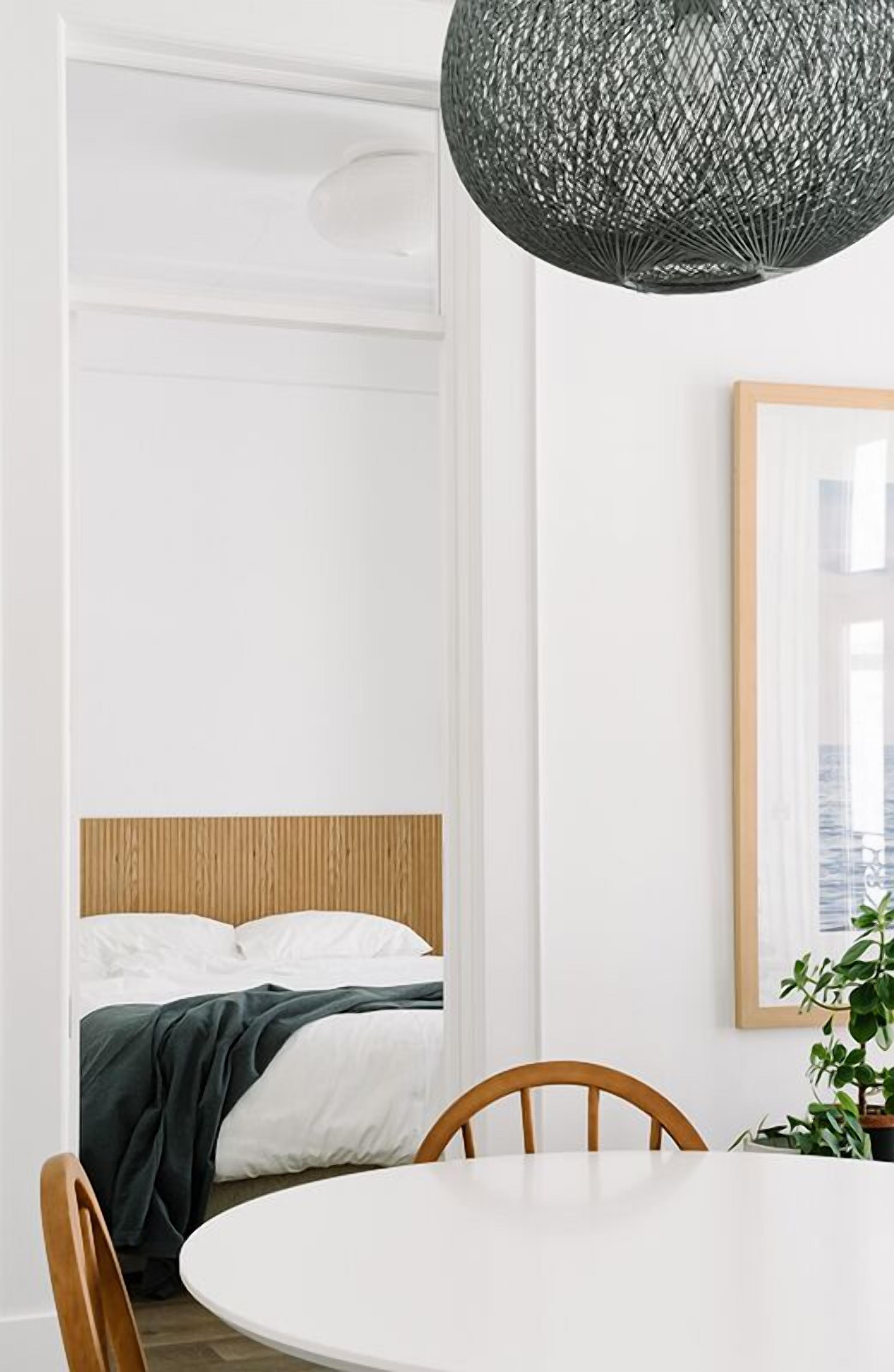 Una habitación moderna con una cama, una mesa de comedor redonda y una lámpara colgante.