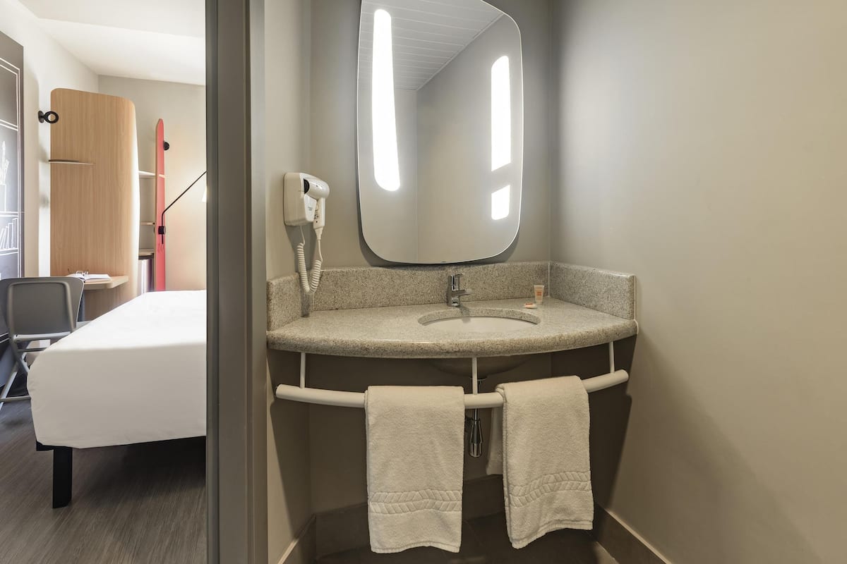 A modern bathroom with a granite countertop, a large mirror, and two towels hanging on a towel bar.