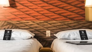 Habitación de hotel con dos camas, pared texturizada e interruptor de pared.