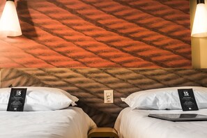 Habitación de hotel con dos camas, pared texturizada e interruptor de pared.