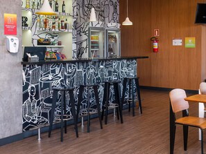 A bar area with a black and white mural, stools, and a refrigerator stocked with beverages. - ibis Guaiba (Guaiba)
