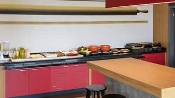 Eine moderne Küche mit einer langen Arbeitsplatte, roten Schränken und einer Bar mit Hockern.
