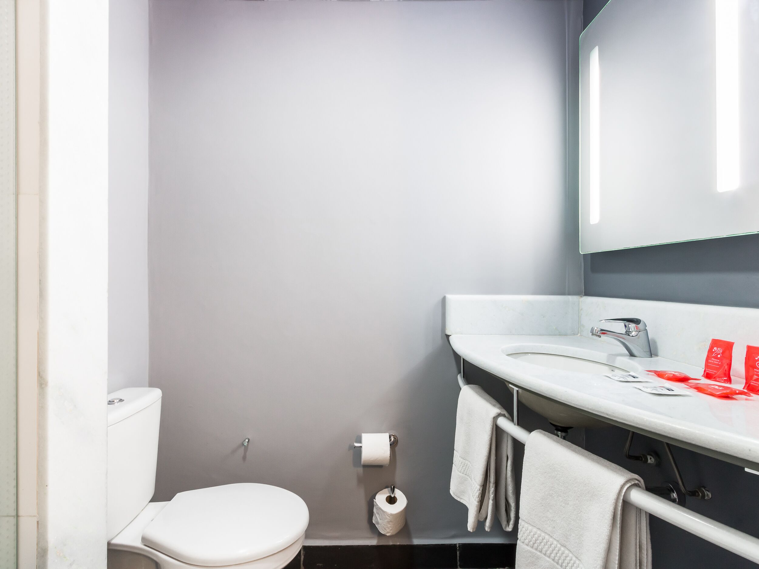A modern bathroom with a toilet, sink, and towel rack.