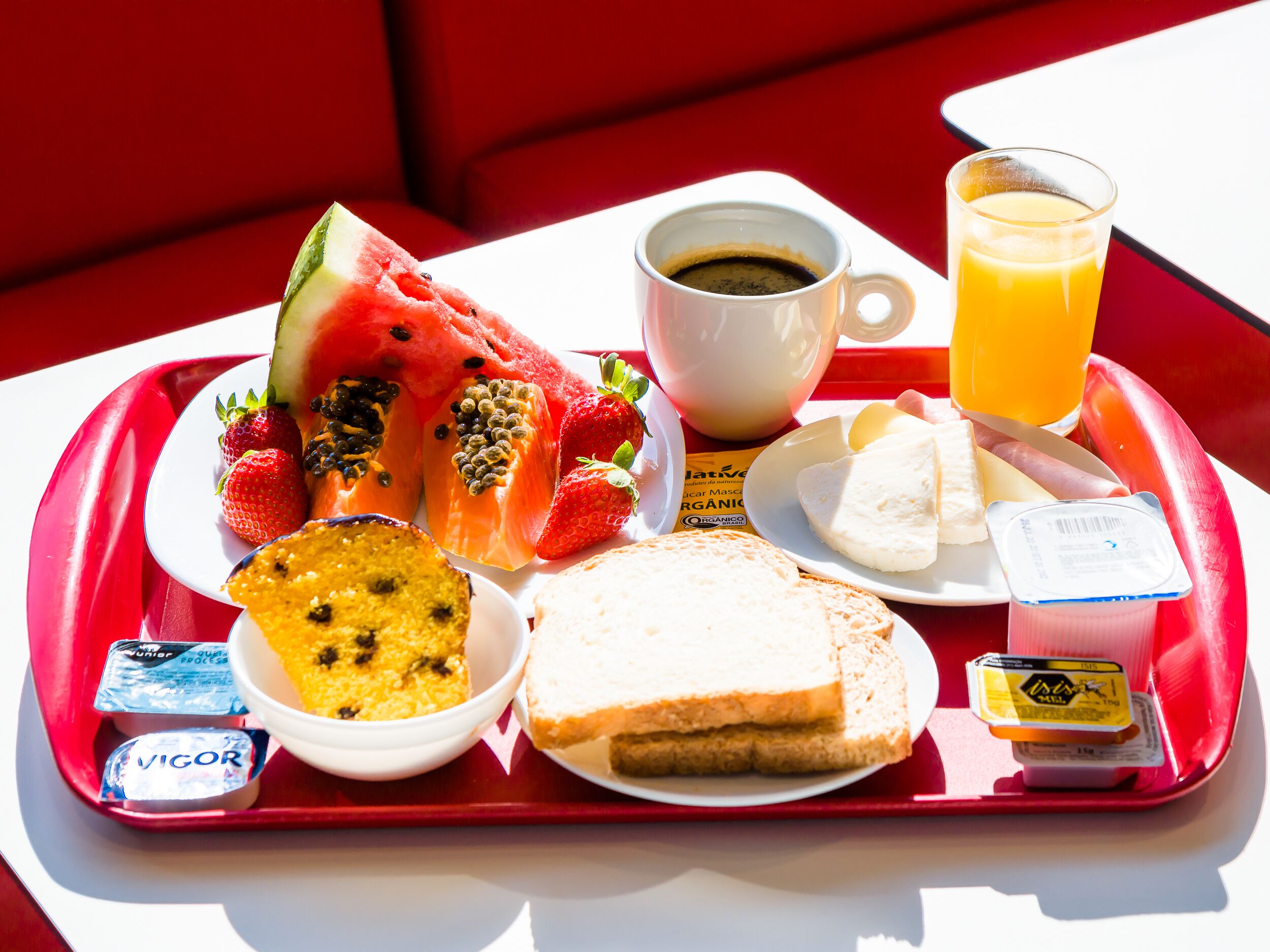 Een ontbijfwagen met diverse soorten eten, zoals toast, yoghurt, fruit en een kop koffie.