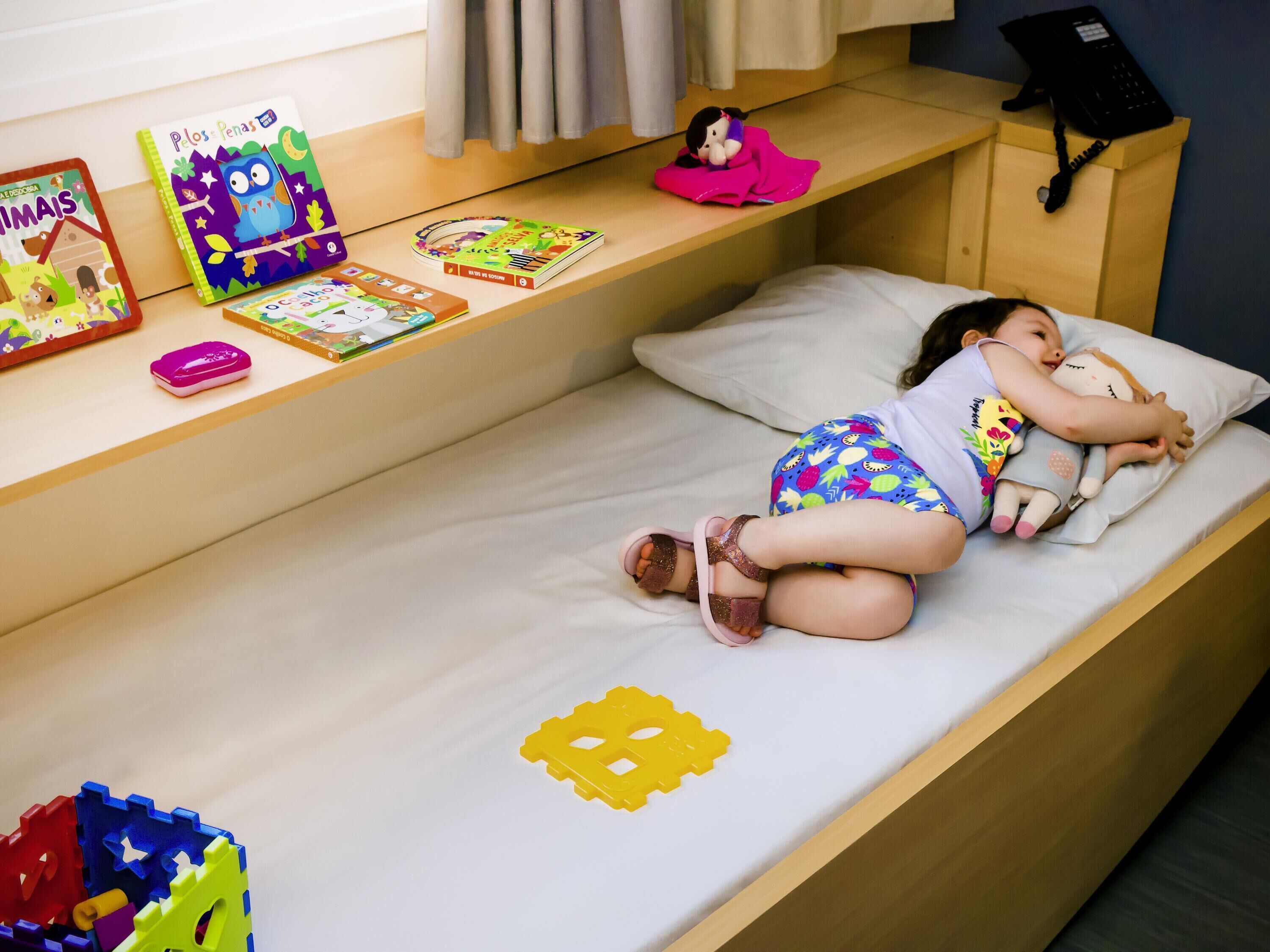 Een kinderkamer met een bed, boeken en speelgoed.