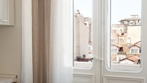A view through a white door with a window, revealing a cityscape with buildings and rooftops. - Palazzo Talenti 1907 (Trieste)